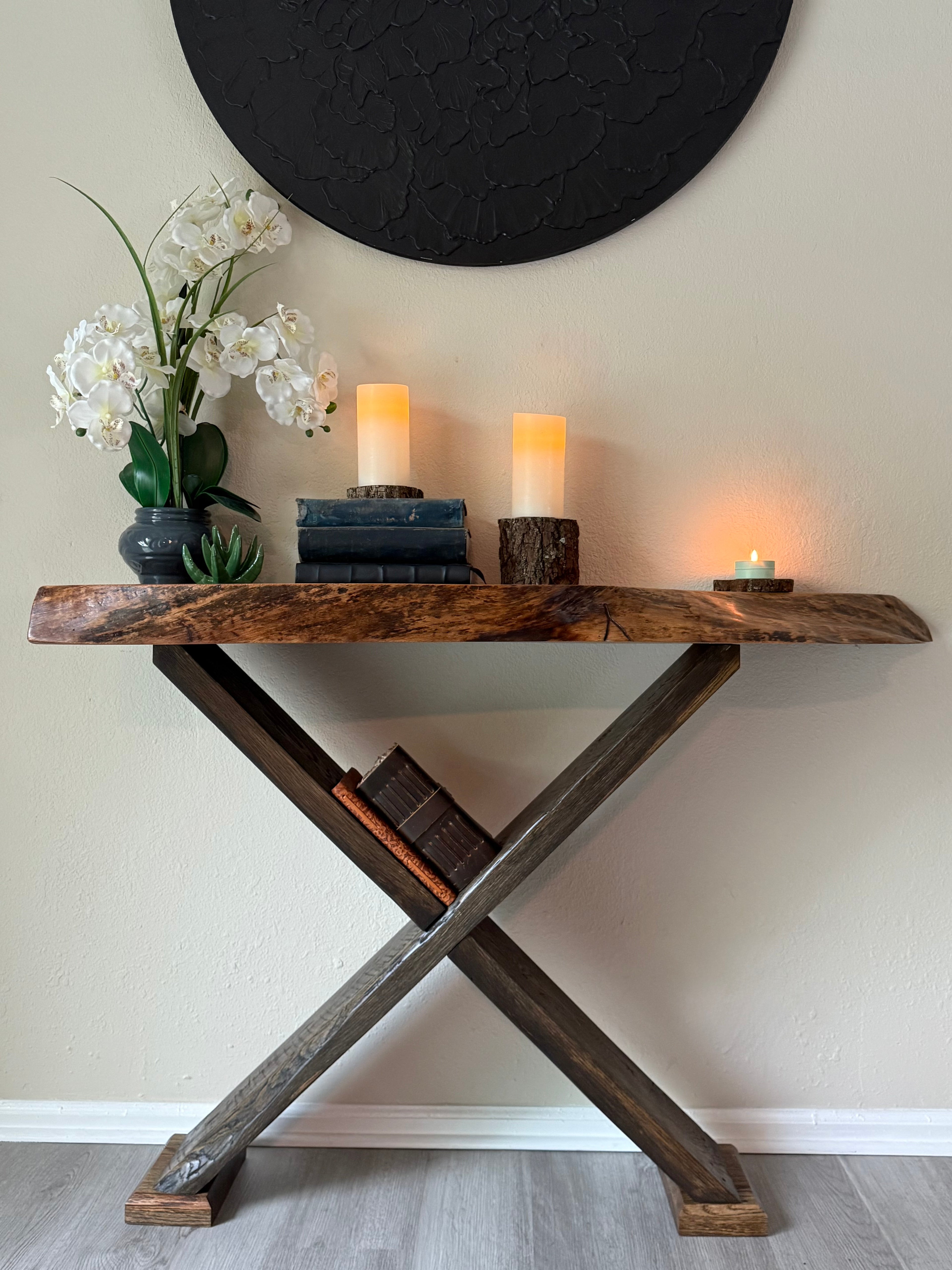 live edge walnut entry table styled with faux orchids, stacked vintage books and candles in a cozy entryway