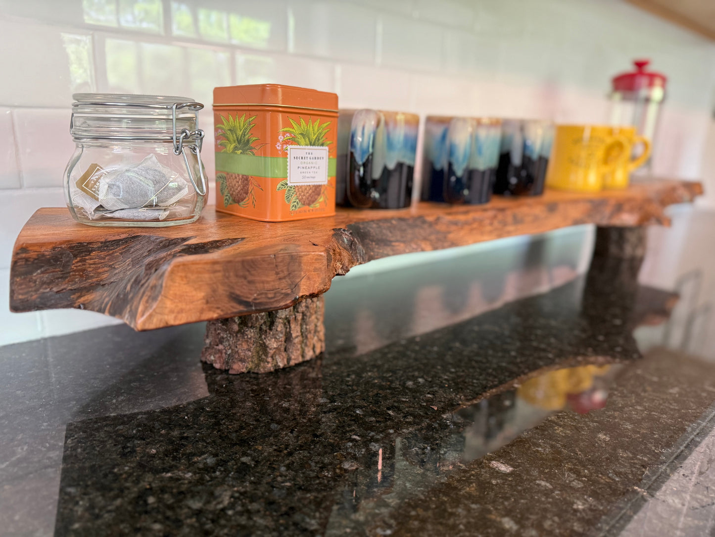 close-up of end grain and the organic shape of this handmade walnut shelf styled with coffee and tea items