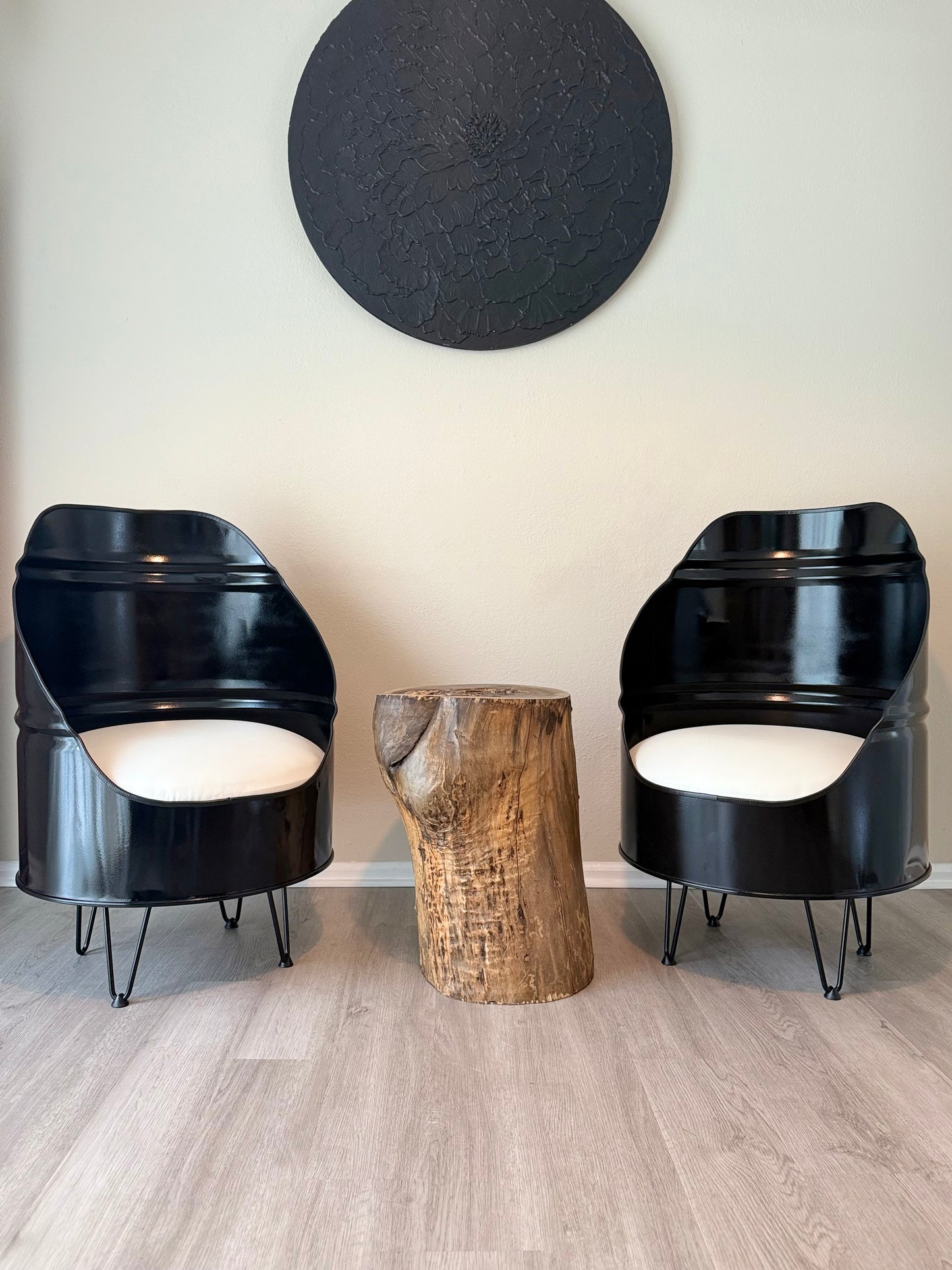 pair of black reclaimed oil drum chairs with white cushions and hairpin legs, styled with a live edge stump table in a modern room