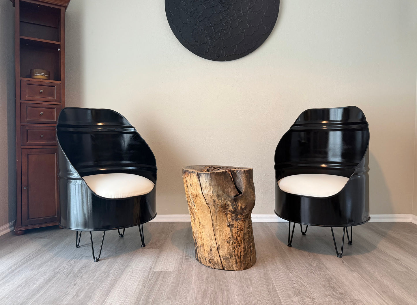 pair of black reclaimed oil drum chairs with white cushions and hairpin legs, styled with a live edge stump table in a living room