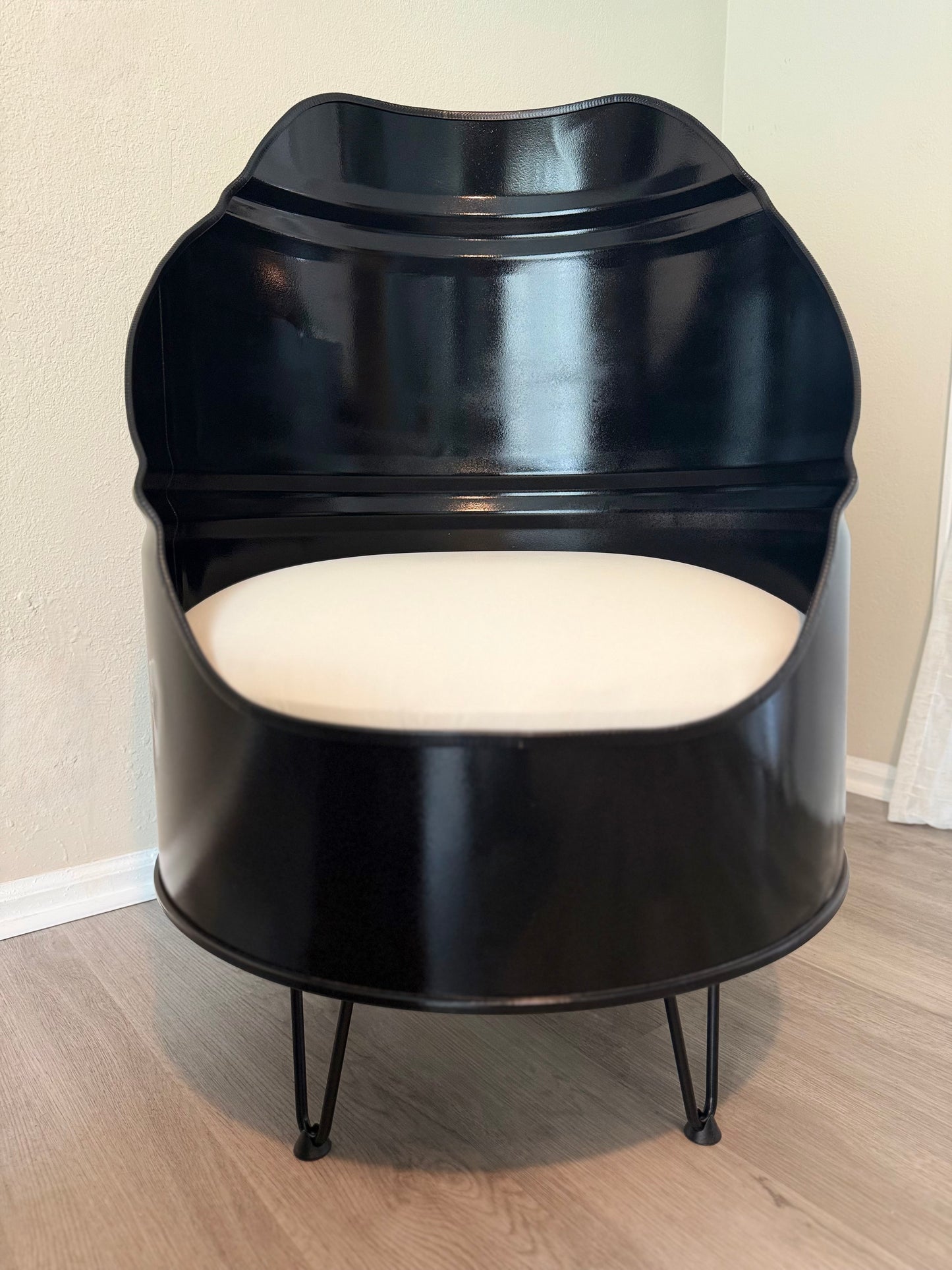close up of handcrafted, reclaimed barrel chairs showcasing shape and textured glossy black enamel paint with hair hairpin legs