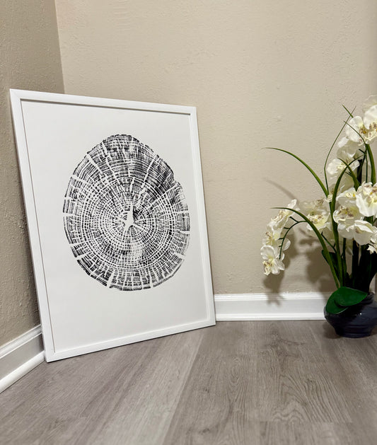 hand pressed tree ring art in black paint on white paper staged in hallway with faux orchids