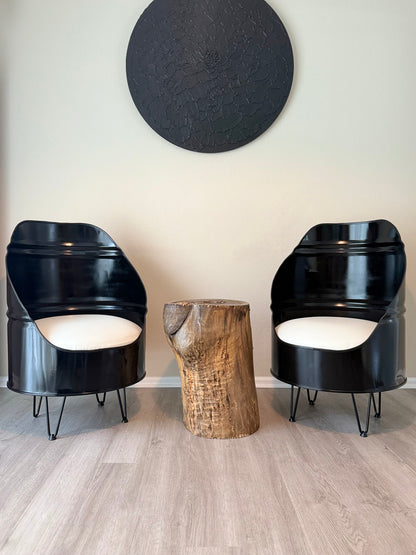 pair of black reclaimed oil drum chairs with white cushions and hairpin legs, styled with a live edge stump table in a modern room