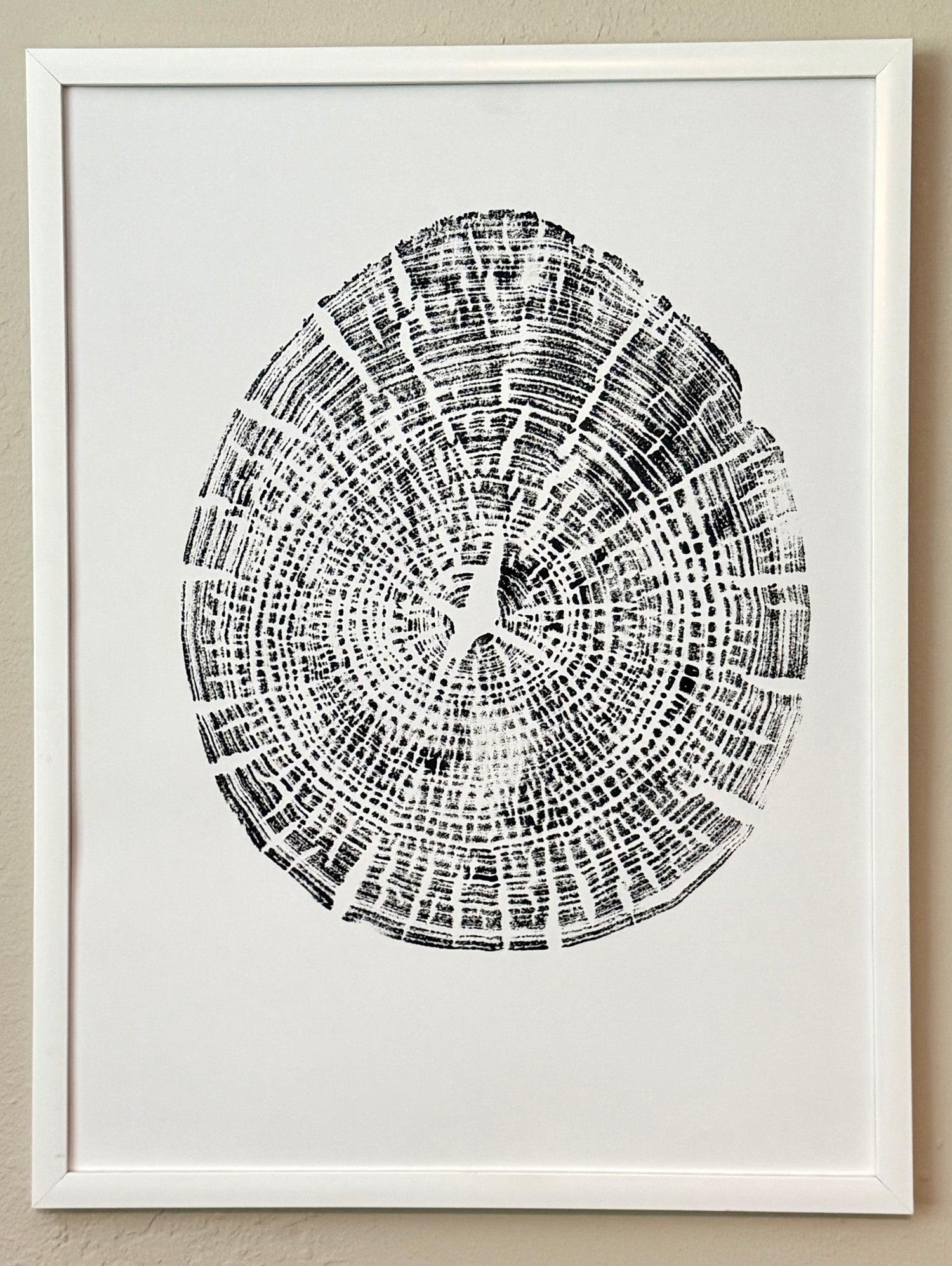 hand pressed tree ring art in black acrylic paint on white paper hanging on wall